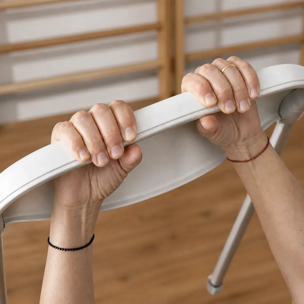 Mani che impugnano lo schienale di una sedia durante una lezione di yoga sulla sedia allo studio Fiorire di Pescara.